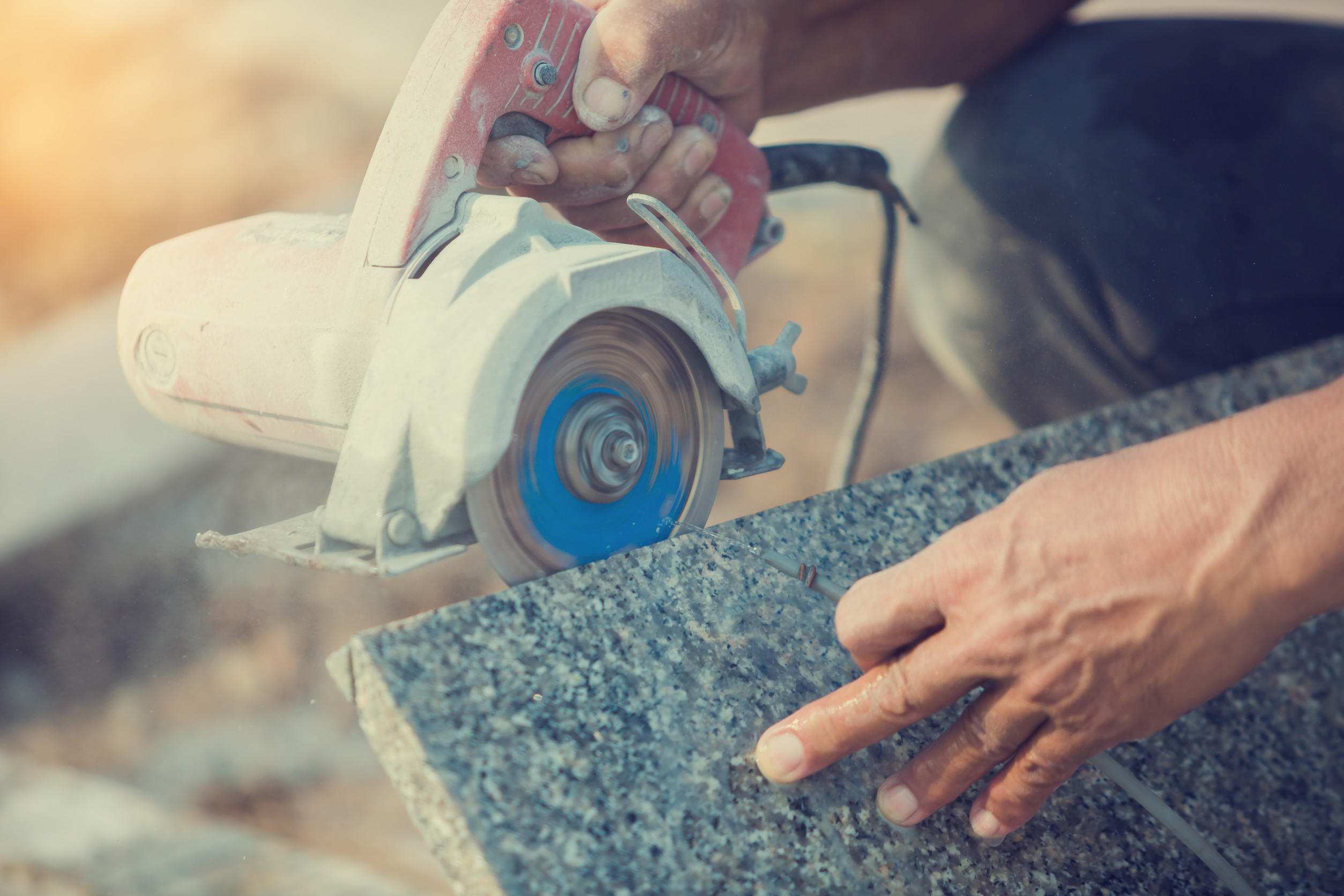 worker cutting granite stone with an diamond electric saw blade